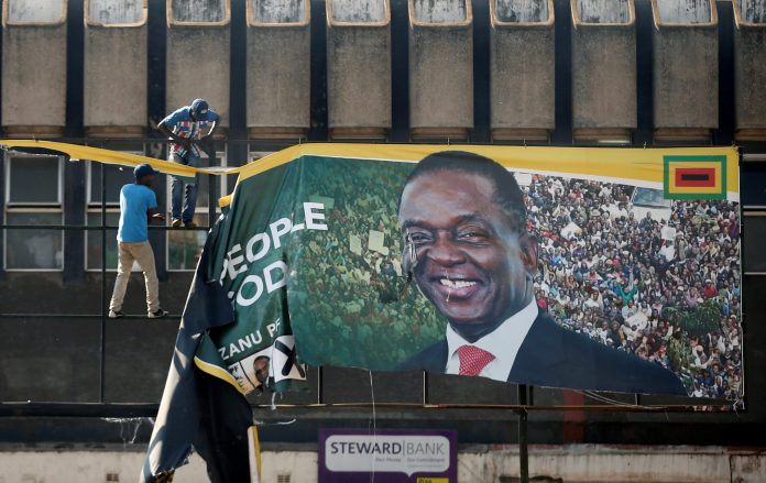 Supporters of the opposition Movement for Democratic Change party (MDC) of Nelson Chamisa remove an election banner with the face of Zimbabwe's President Emmerson Mnangagwa in Harare