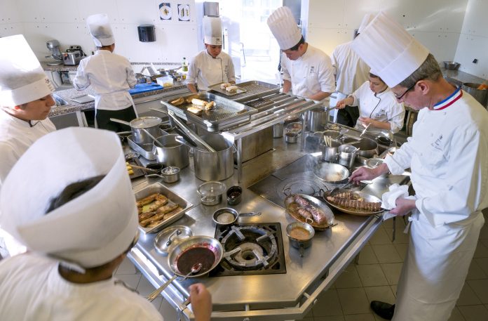 Students work in the kitchen of the teaching restaurant managed by French chef Alain Lecossec at the Institut Paul Bocuse, in a 19th century chateau, in Ecully near Lyon
