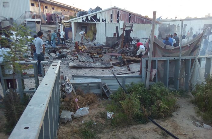 People check the damaged after a rocket hit a camp for displaced people during the fight between rival armed groups in Tripoli