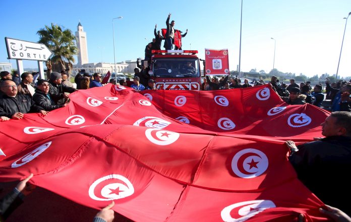 Tunisian police officers and security personnel shout slogans and hold flags during a protest in Tunis