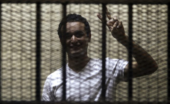 Egyptian activist Ahmed Douma gestures from behind bars during his trial at the New Cairo court, on the outskirts of Cairo