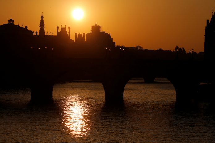 The sun rises above the Seine River skyline in central Paris