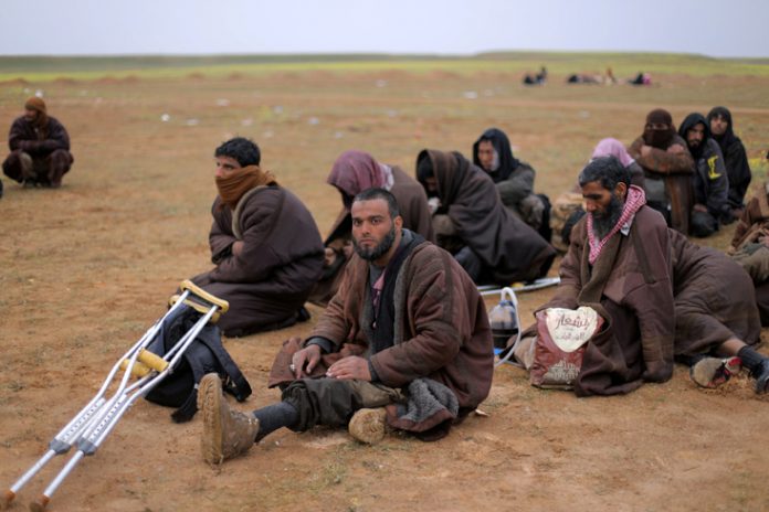Men sit together near the village of Baghouz