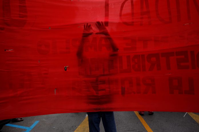A supporter of the Communist party uses a scissors to make holes on a banner as he takes part in a May Day rally in Malaga