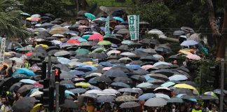 Demonstranter med paraplyer i demonstrasjonstoget organisert av lærere i Hongkong lørdag. Foto: Vincent Yu / AP / NTB scanpix